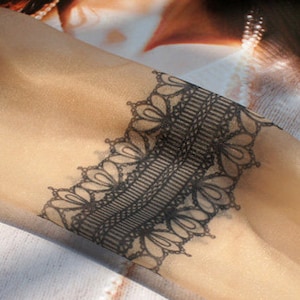 May include: Black lace trim with a delicate floral pattern. The trim is made of a sheer fabric and has a slightly raised texture.