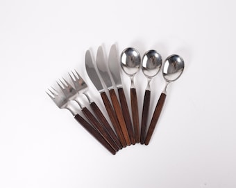 May include: A set of vintage silverware, including forks, knives, and spoons. The utensils have stainless steel heads and dark brown wooden handles. The arrangement is fanned out on a white background.