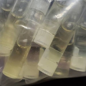 May include: A clear plastic bag filled with many small, clear glass bottles with white caps. The bottles are filled with a clear liquid.