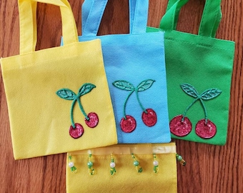 May include: Four small tote bags with cherry designs. The bags are yellow, blue, green, and yellow. The yellow bags have a beaded trim.