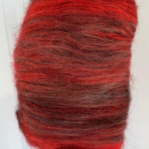 May include: A bundle of red and black wool roving. The roving is soft and fluffy, and it is perfect for spinning or felting.