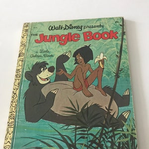 May include: A vintage Walt Disney Presents The Jungle Book Little Golden Book featuring Mowgli sitting on Baloo the bear. The cover is green and features a jungle scene with a banana.