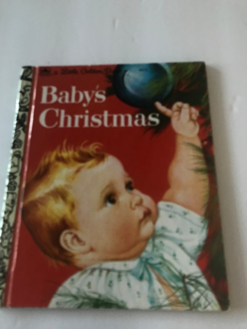 May include: A vintage children's book titled "Baby's Christmas" with a red cover. The cover features an illustration of a baby reaching for a Christmas ornament. The book has a gold spine.