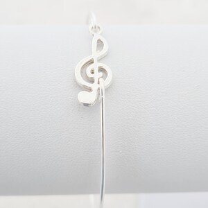 May include: A silver bracelet with a treble clef charm.