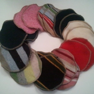 May include: A circular arrangement of assorted fabric coasters. The coasters are in various colors, including pink, red, black, and cream, and feature different patterns like stripes and solid colors. Each coaster has a brown border.