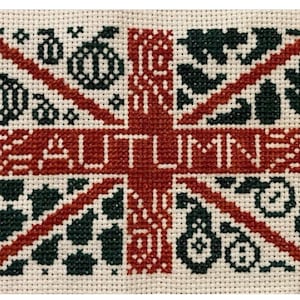May include: Cross-stitch design featuring the word "AUTUMN" in red, overlaid on a Union Jack pattern. The design incorporates pumpkins, leaves, and other fall-themed motifs in dark green and red on a cream background.