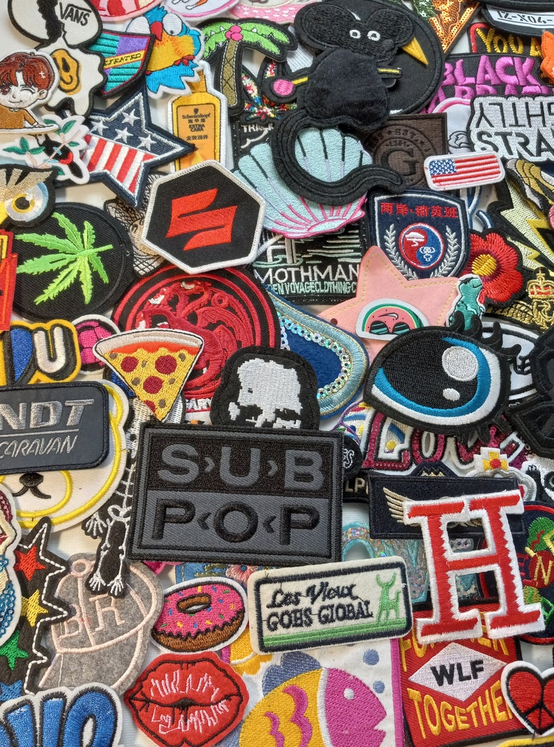May include: A collection of colourful embroidered patches featuring various designs, including a pizza slice, a donut, a fish, a seashell, a palm tree, a black cat, a marijuana leaf, a red and white striped star, a red and white striped heart, a red and white striped flag, a red and white striped letter H, a red and white striped letter U, a red and white striped letter N, a red and white striped letter D, a red and white striped letter T, a red and white striped letter C, a red and white striped letter A, a red and white striped letter R, a red and white striped letter V, a red and white striped letter A, a red and white striped letter N, a red and white striped letter S, a red and white striped letter P, a red and white striped letter O, a red and white striped letter P, a red and white striped letter S, a red and white striped letter U, a red and white striped letter B, a red and white striped letter P, a red and white striped letter O, a red and white striped letter P, a red and white striped letter L, a red and white striped letter E, a red and white striped letter S, a red and white striped letter V, a red and white striped letter I, a red and white striped letter E, a red and white striped letter U, a red and white striped letter X, a red and white striped letter G, a red and white striped letter O, a red and white striped letter E, a red and white striped letter S, a red and white striped letter G, a red and white striped letter I, a red and white striped letter O, a red and white striped letter B, a red and white striped letter A, a red and white striped letter L, a red and white striped letter W, a red and white striped letter L, a red and white striped letter F, a red and white striped letter T, a red and white striped letter O, a red and white striped letter G, a red and white striped letter E, a red and white striped letter T, a red and white striped letter H, a red and white striped letter E, a red and white striped letter R, a red and white striped letter E, a red and white striped letter  and a red and white striped letter  .