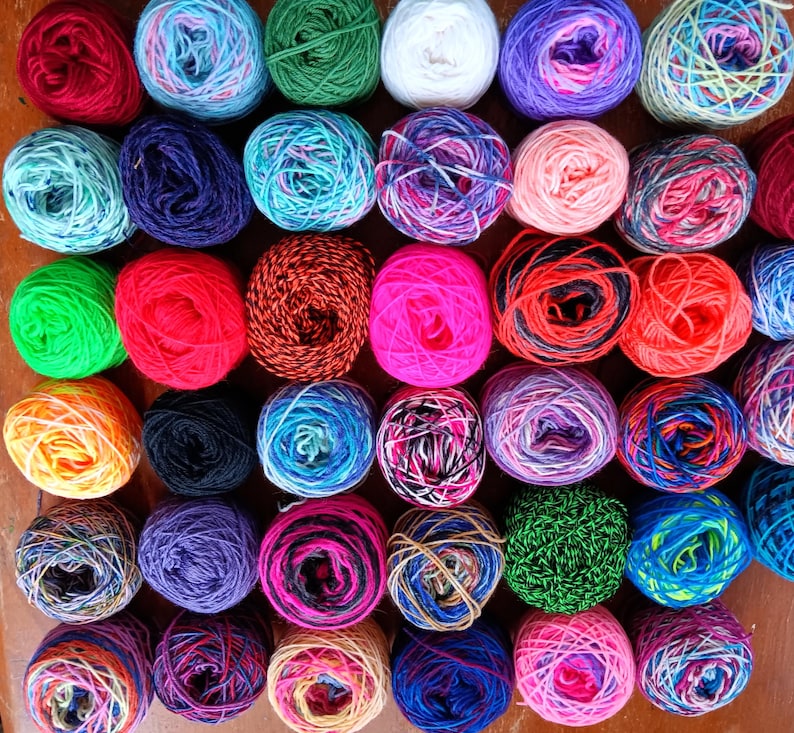 May include: A collection of 40 colorful yarn skeins in various shades of blue, green, red, pink, yellow, and white. The yarn is arranged in a grid pattern.