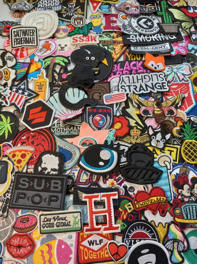 May include: A collection of colourful embroidered iron-on patches featuring various designs, including animals, food, words, and logos. The patches are perfect for adding a personalised touch to clothing, bags, and other accessories.