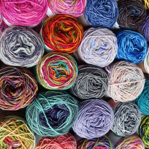 May include: A collection of colorful yarn skeins in various patterns and textures. The yarn is arranged in a circular pattern, with each skein touching the others. The yarn is a mix of bright and muted colors, including red, blue, green, yellow, and purple.