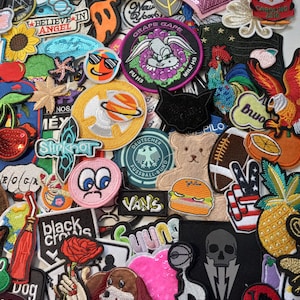 May include: A collection of colourful embroidered iron-on patches featuring various designs, including animals, food, and text. The patches are perfect for adding a personal touch to clothing, bags, and other accessories.