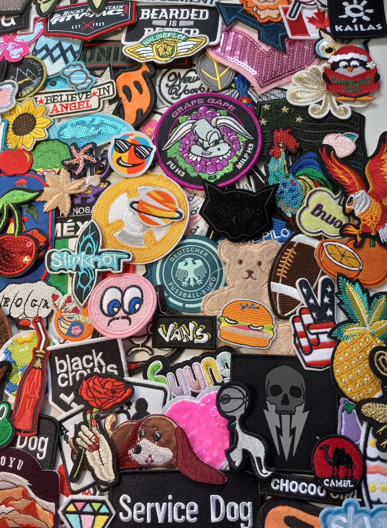 May include: A collection of colourful embroidered iron-on patches featuring various designs, including animals, food, and text. The patches are perfect for adding a personal touch to clothing, bags, and other accessories.