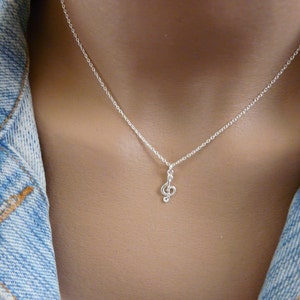 May include: A silver chain necklace with a small treble clef pendant.