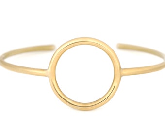 May include: A gold-toned circle bangle bracelet with a large, open circle design.
