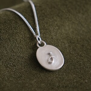 embossed raised initial letter on oval charm pendant with antique matte finish