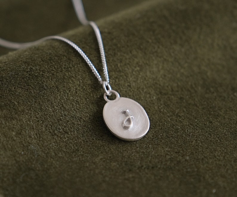 embossed raised initial letter on oval charm pendant with antique matte finish