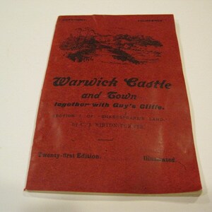 May include: A red book cover with the title "Warwick Castle and Gown together with Guy's Cliffe." The book is the twenty-first edition and is illustrated.