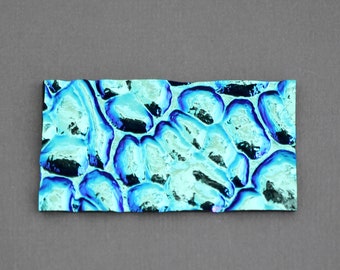 May include: A close-up of a blue and silver iridescent textured sheet. The sheet has a pattern of overlapping circles.