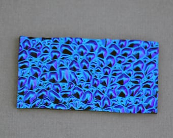 May include: A close-up of a blue and purple iridescent fabric with a textured, geometric pattern.