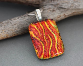 May include: A rectangular glass pendant with a silver bail. The glass is red, orange, and yellow with a wavy pattern.