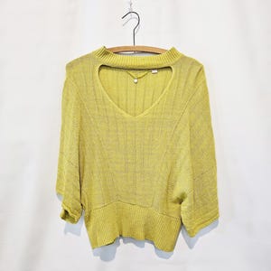 May include: A yellow knitted sweater with a keyhole neckline and short sleeves.