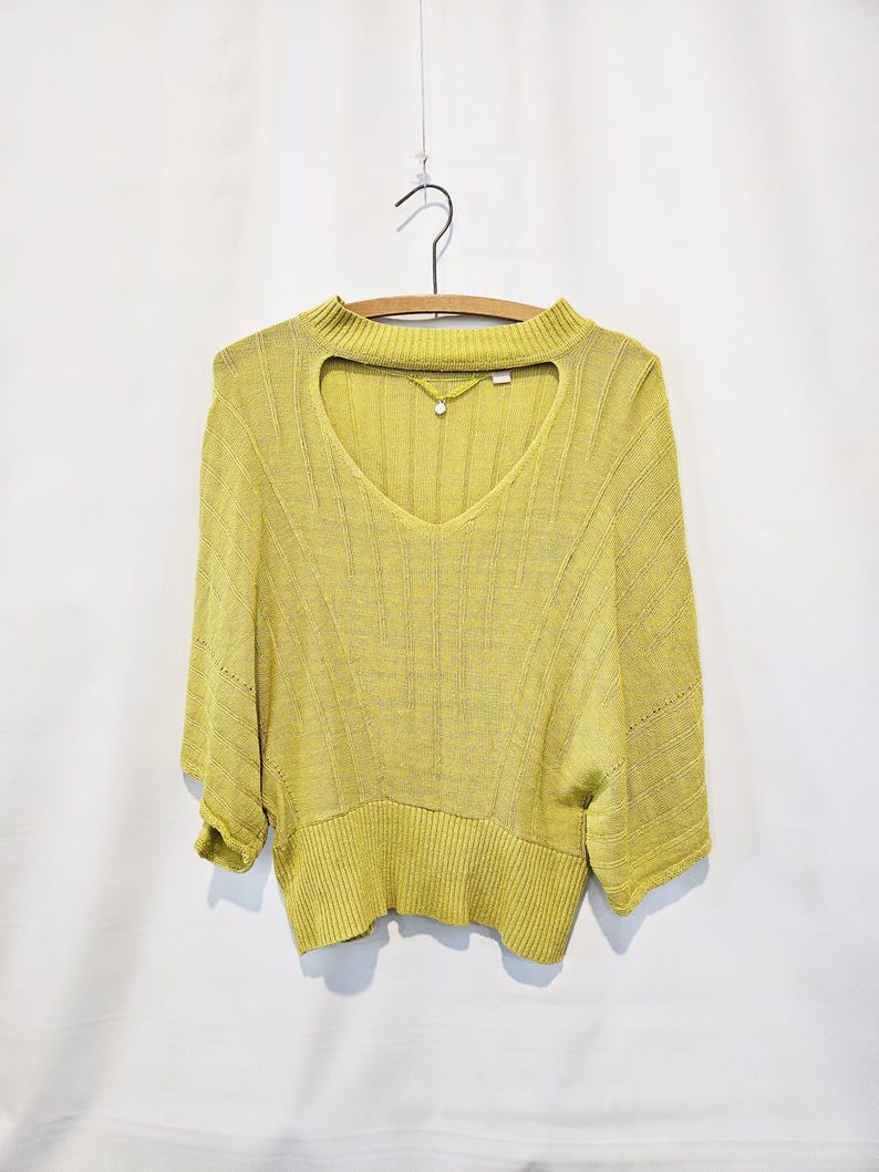 May include: A yellow knitted sweater with a keyhole neckline and short sleeves.