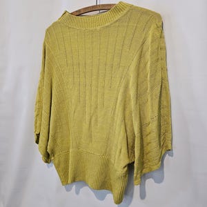 May include: A yellow knitted sweater with a round neckline and short sleeves. The sweater has a ribbed texture and a slightly cropped length.