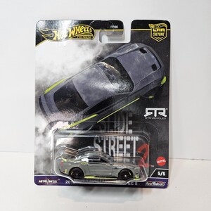 以下が含まれることがあります： ライムグリーンのアクセントが入ったグレーのHot Wheelsプレミアムダイキャスト製ミニカー。Slide Streetと書かれた黒いブリスターカードに梱包されています。パッケージにはHot Wheelsのロゴ、Car Cultureのブランド名、RTR Vehiclesのロゴ、そして5/5という数字が記載されています。
