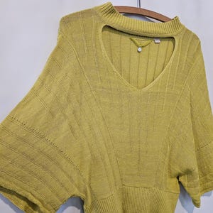 May include: A yellow knitted sweater with a keyhole neckline and short sleeves.