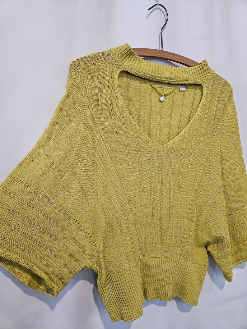May include: A yellow knitted sweater with a keyhole neckline and short sleeves.