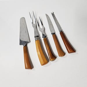 May include: A set of vintage serving utensils with stainless steel blades and brown handles. The set includes a cake server, two forks, and two knives. The handles have a curved design and a glossy finish.