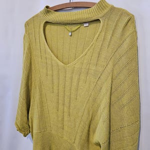 May include: A yellow knitted sweater with a keyhole neckline and a ribbed texture.