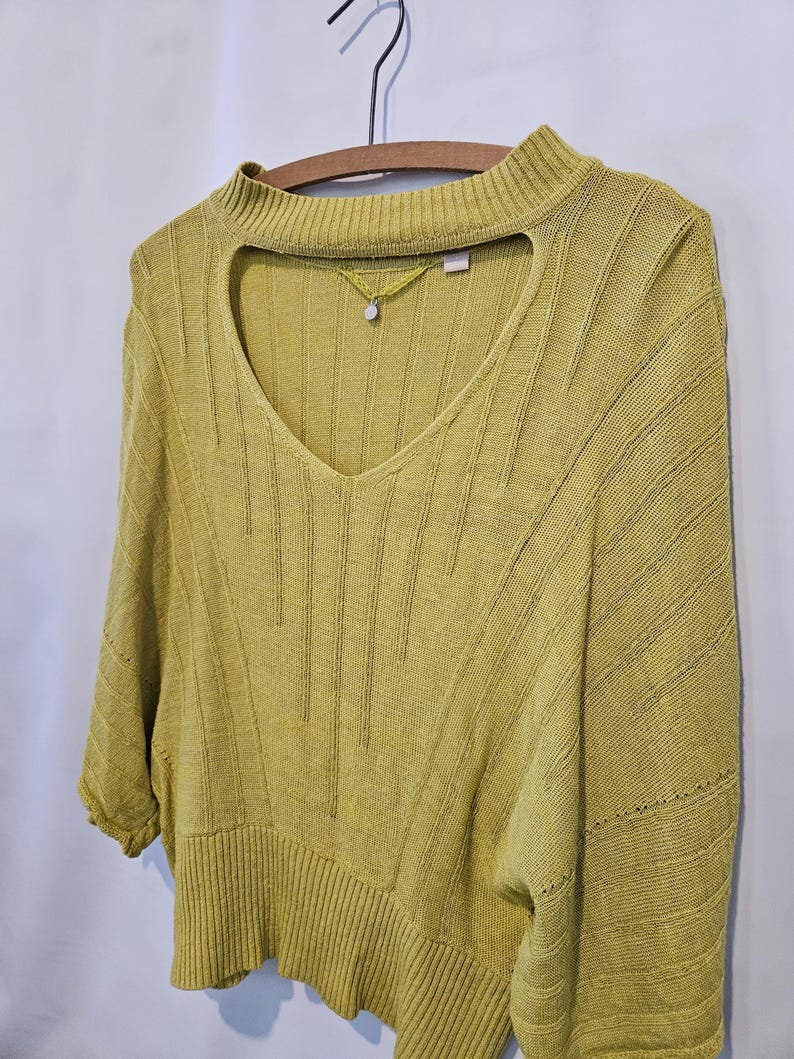 May include: A yellow knitted sweater with a keyhole neckline and a ribbed texture.