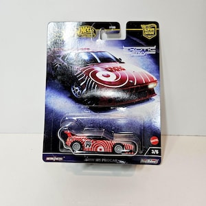 May include: A Hot Wheels Premium BMW M1 Procar die-cast toy car in red and white livery with the number 79, packaged on a blister card from the Exotic Envy series. The card features a graphic of the car and text including Hot Wheels and 3/5.