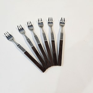 Puede incluir: Seis tenedores de plata con mangos de madera marrón. Los tenedores están dispuestos en forma de abanico.