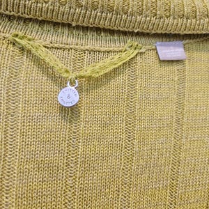 May include: A close-up of a yellow knitted sweater with a small silver tag that says "Knitted & Knotted".