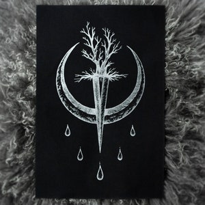 May include: A black art print featuring a white illustration of a tree pierced by a sword, set within a crescent moon. Below the moon are five teardrop shapes. The artwork is set against a textured, gray background.