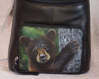 Leather Top Flat Zippered Backpack with a hand painted portrait Shenan, a black bear cub.