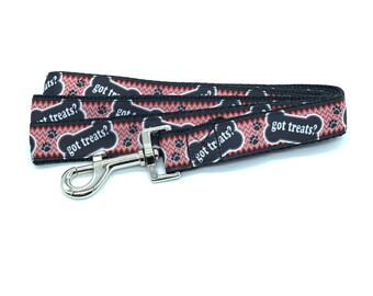 May include: Black and red dog leash with a paw print and bone design. The leash has the text "got treats?" repeated on it.