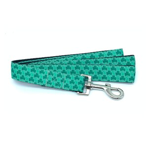 May include: Green dog leash with a shamrock pattern and a silver clip.