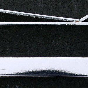 May include: Two silver-colored tie clips are displayed against a dark background. The top clip is a curved bar with a hinged section. The bottom clip is a flat, rectangular bar with rounded edges. Both are highly reflective.