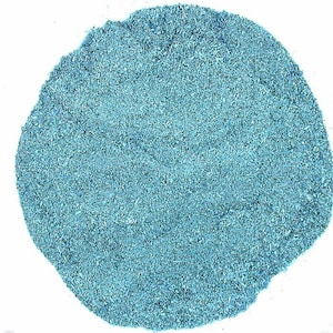 May include: A close-up shot of a pile of fine, light blue powder against a white background. The powder has a slightly textured appearance, with small particles visible. The overall shape is irregular, resembling a small mound.