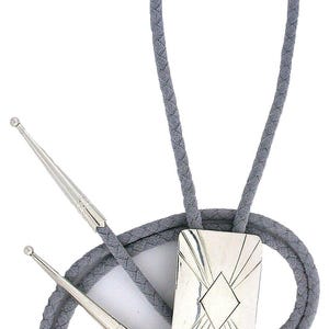 May include: A gray bolo tie with a braided cord and silver-toned metal accents. The rectangular pendant features a diamond-shaped center and linear design. The tie's tips are also silver-toned.