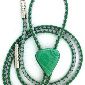 May include: A bolo tie featuring a triangular malachite stone with distinct green banding. The cord is braided with alternating green and grey segments, finished with polished silver-toned metal tips at the ends of the cord for a secure closure.