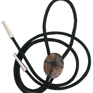 May include: A bolo tie featuring a black braided cord with silver-toned metal tips. The central focal point is an oval-shaped stone with a brown and gray surface displaying a dark, cross-like pattern across its polished, smooth texture.