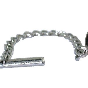 May include: A silver-toned tie tack featuring a circular head set with a single round, faceted, vibrant pink gemstone. The circular head is connected by a short, delicate silver-toned chain to a horizontal bar-shaped backing piece.