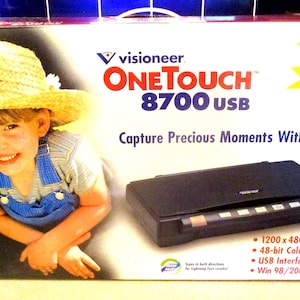 May include: A box for a Visioneer OneTouch 8700 USB scanner. The box is red and white with a picture of a child wearing a straw hat and a blue overall. The scanner is black and has a blue button on the right side. The box says "Perfect for the Photo Enthusiast!" and "Capture Precious Moments With OneTouch!" The box also lists the scanner's features: 1200 x 4800 dpi, 48-bit color, USB interface, and compatible with Windows 98/2000/ME/XP.