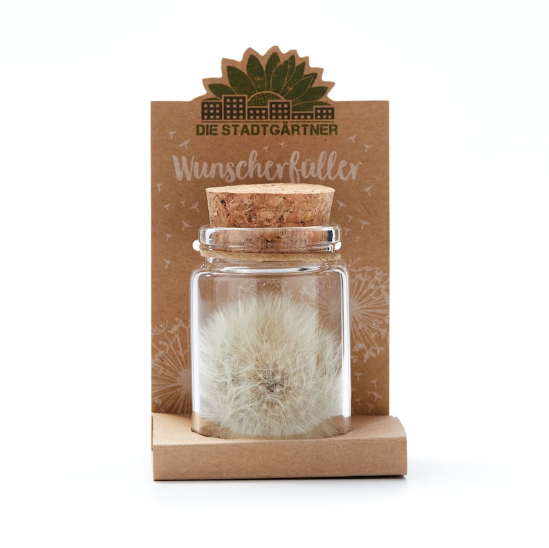 May include: A small glass jar with a cork lid containing a dried dandelion seed head. The jar is labeled "Wunscherf&uuml;ller" and "Die Stadtg&auml;rtner".