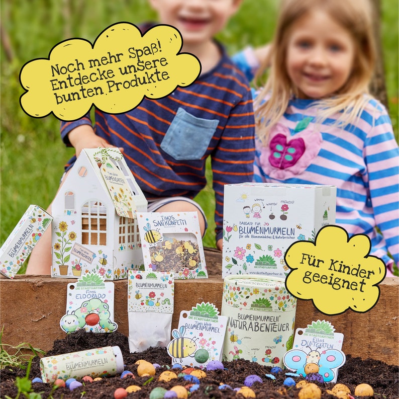 May include: A set of colorful flower seed balls, a small paper house, and a box of flower seeds. The packaging features illustrations of bees, flowers, and children. The text on the packaging reads "BLUMENMURMELN" and "F&uuml;r Kinder geeignet".