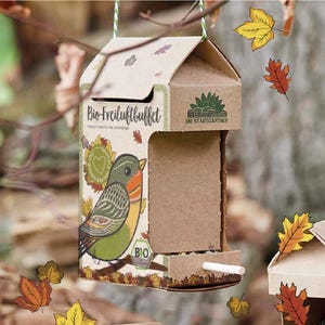 Könnte beinhalten: Ein Vogelhäuschen aus Pappe in Form eines Hauses mit einer Vogel-Illustration und dem Text "Bio-Freiluftbuffet" und "Die Stadtgärtner".